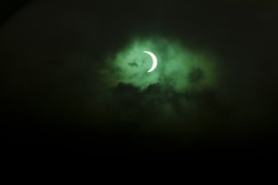 Partial solar eclipse on a dark black clouds in the sky. 