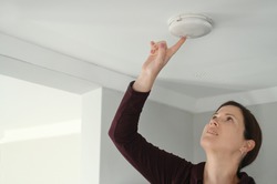 Young adult woman (female age 25-35) checking fire alarm at home.Real people. Copy space