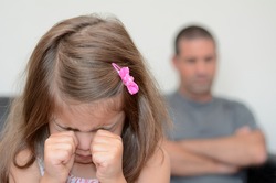 Young sad girl (age 05) crying while her desperate father sitting upset in background. Real people. Copy space