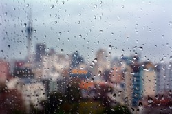 Urban view of rain drops falls on a window during a stormy day overlooking Auckland financial district  New Zealand skyline in the background.