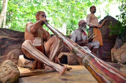 Australian Aboriginal men play Aboriginal music on didgeridoo and wooden instrument during Aboriginal culture show in Queensland, Australia.