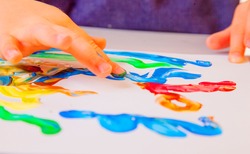 Art, creativity, beauty childhood concept. Little child girl painting with colorful hands.