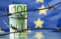 Conceptual image of European Union currency wrapped in barbed wire against flag of EU as symbol of Economic warfare, sanctions and embargo busting.