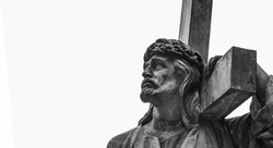 Ancient statue of Jesus Christ with cross. Selective focus on eyes. Free copy space. Horizontal image.
