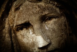 Fragment of antique statue of crying Virgin Mary. Tears on her face as symbol of pain, death and resurrection of Jesus Christ. Fragment of an ancient statue. Horizontal image.