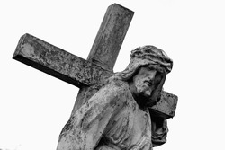 The road to Golgotha. Ancient statue of Jesus Christ with cross against white background. 