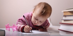 beautiful little baby girl is writing letter