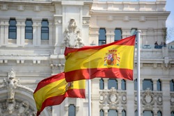 Flag of Spain in the wind in front of Palace of Communication (Spanish: Palacio de Comunicaciones) in Madrid, Spain