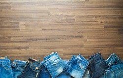 Jeans stacked on a wooden background, View from above with copy workspace