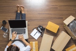 Top view of women working laptop computer from home on wooden floor with postal parcel, Selling online ideas concept