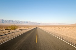 Long straight tarmac road heading into the desert of Death Valley