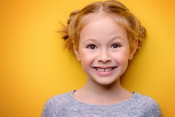 Close-up portrait of a cute little girl. Studio shot over yellow background. Childhood concept.