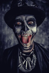Close-up portrait of a man with a skull makeup dressed in a tail-coat and a top-hat. Baron Saturday. Baron Samedi. Dia de los muertos. Day of The Dead. Halloween.