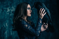 A witch in hat and dress with a raven. Halloween. Celebration.
