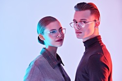 Fashion studio shot. Handsome young man and beautiful young woman posing together in stylish glasses. Optics. Business style.