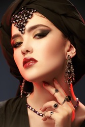 Beautiful oriental woman with traditional make-up, black hijab and jewelry on a black background. Arabian beauty, fashion. Make-up and cosmetics. Jewelry.