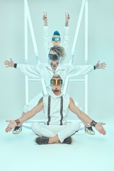 Group of punk rock musicians in white overalls and cool cyber glasses pose at the studio in neon light. Youth alternative culture. Full length shot.