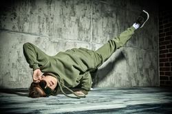 Full length portrait of a boy dancing break dance in the studio on a grunge background. Contemporary dances. Sports and active lifestyle. 