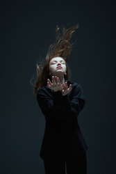 Art portrait of a beautiful young girl with long flying hair and closed eyes. The inner world of a human, emotions. Thoughtfulness, meditation. Studio portrait on a dark background.