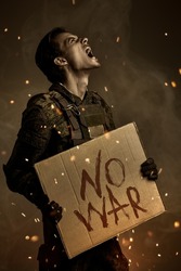 No War concept. Angry soldier in Protective Combat Uniform holds a sign 