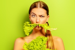Pretty cheerful young woman posing with fresh green lettuce leaves. Healthy eating concept. Dieting.