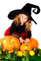 Cute little girl in a witch costume posing with pumpkins. Halloween. 
