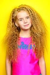 Joyful little girl with beautiful blonde hair over yellow background. Kid's style. Hairstyle.