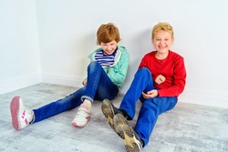 Joyful laughing children sitting together on a floor. Children's fashion. Education. Happiness, activity and child concept. Copy space.