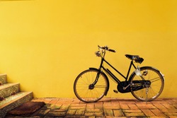 A Vintage bicycle park in front of the yellow fresco painting wall