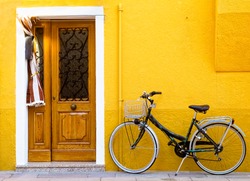 Colorful house on the island of Burano with a bike near the entrance