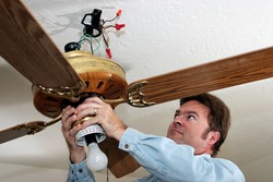 An electrician removing an old ceiling fan.  The fan was installed without a ceiling box, in violation of code.