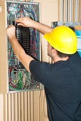 Electrician changing a breaker in a large industrial breaker panel.