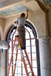 Woman on ladder restoring ceiling