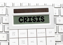 Word crisis on the screen of the calculator located on a computer keyboard. Concept in business. Global economic crisis related to coronavirus.