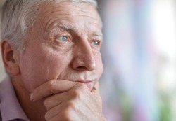 close-up portrait of a senior man thinking about something