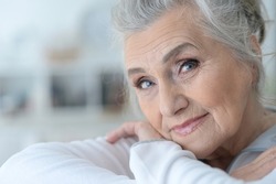 Close up portrait of smiling senior woman posing at home