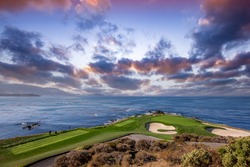 oceanside golf course with bunker,  ocean and clouds