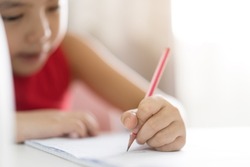 closeup hand of asian child or kid girl enjoy writing learning by left-handed and doing homework or person learn from home and practicing write by pencil on paper book and studying on back to school