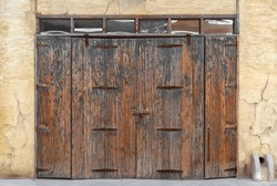 old brown wood door vintage and retro style or ancient house double wooden doors with hinge and lock to close on yellow golden crack cement wall background for home texture backdrop at al seef dubai