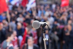 Protest. Public demonstration. Microphone in focus against blurred audience.