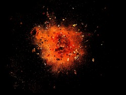Explosion of red cayenne pepper with flakes and seeds on black background