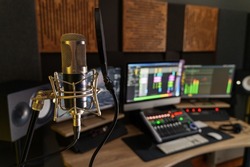 Professional microphone in a small music sound production studio workstation - digital equipment in the production studio room, with mixer, computers and speakers