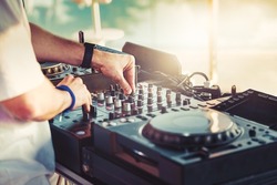 DJ is mixing music with deejay controller at outdoor summer pool or beach party - nightlife people lifestyle concept