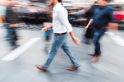picture with camera made motion blur effect of unrecognizable men walking on a busy city street