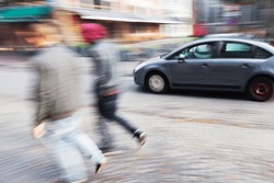 abstract blurred image of a walking couple and driving car on a city street