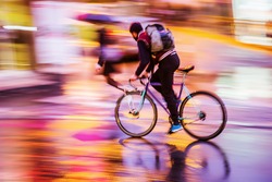 picture with camera made motion blur effect of a bicycle rider at night traffic