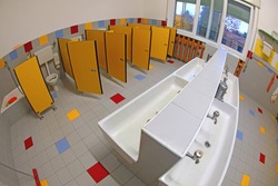 interior of the public bathroom of a kindergarten without children with small sinks and yellow doors photographed with fisheye lens