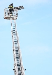 brave firefighter who saves the injured person using the truck with the ladder truck during an emergency and sky on background