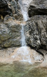 clear spring water that flows from the rock forming a waterfall