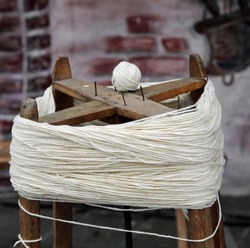 antique wooden spinning wheel also called Swift with the skein of wool below and the ball of yarn